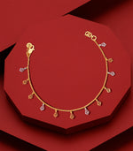 Gold bracelet with geometric charms on a red background