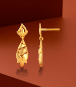 Gold earrings on a brown background