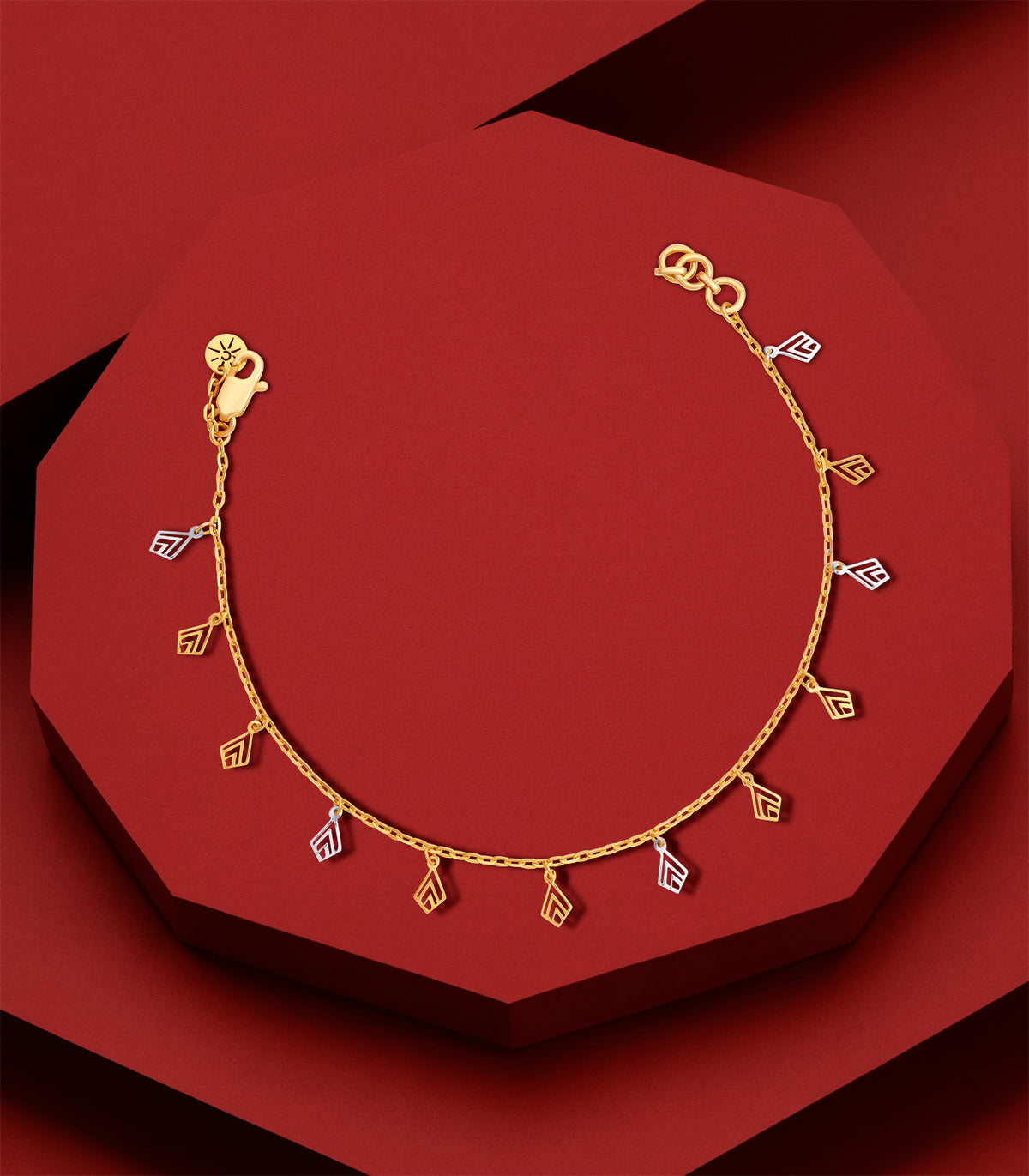 Gold bracelet with geometric charms on a red background