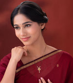 Woman wearing a delicate mangalsutra with a heart-shaped pendant on a red background