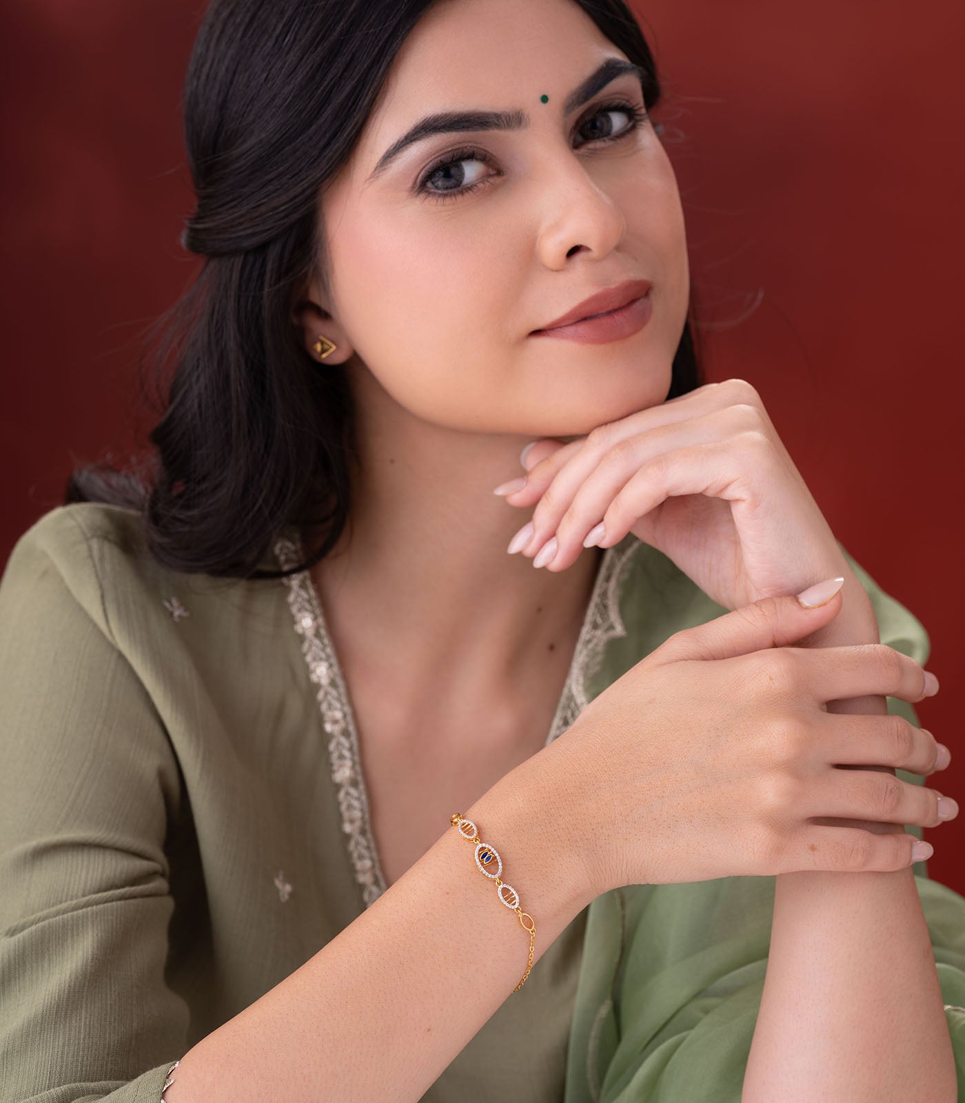 Woman wearing a gold bracelet on a red background