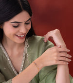 Woman wearing a gold bracelet on her wrist against a red background