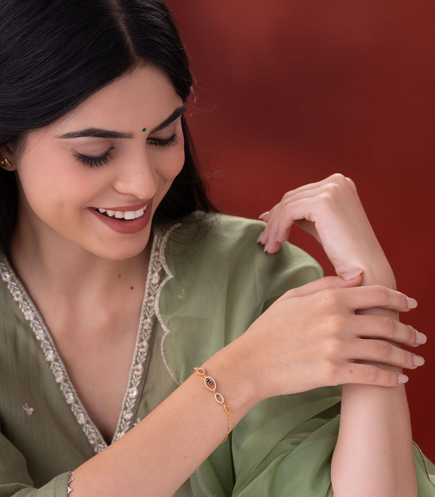 Woman wearing a gold bracelet on her wrist against a red background