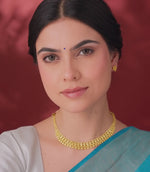 A woman flaunting a gold necklace and earrings on a red background