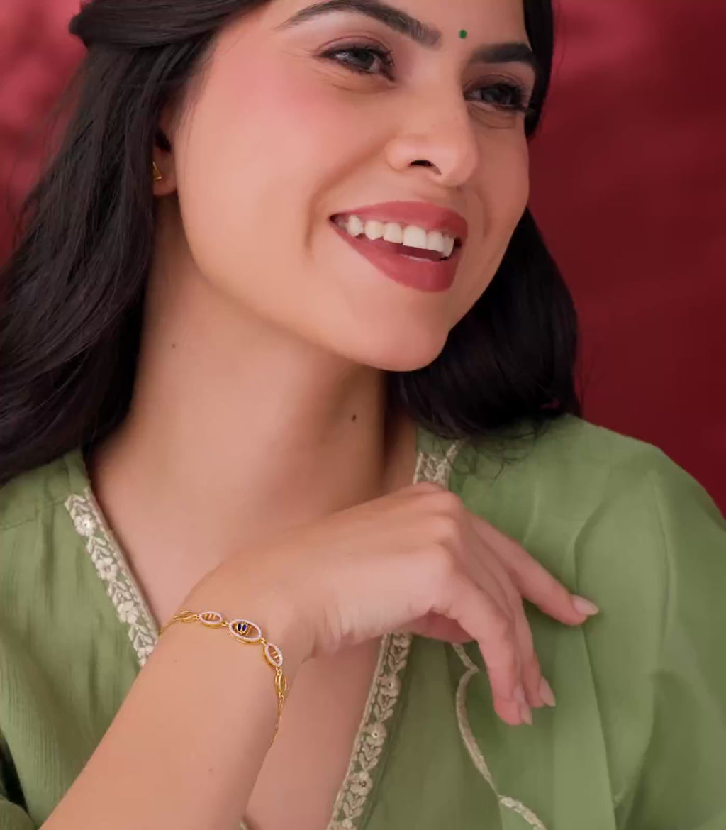 A Woman flaunting a gold bracelet on her wrist against a red background.