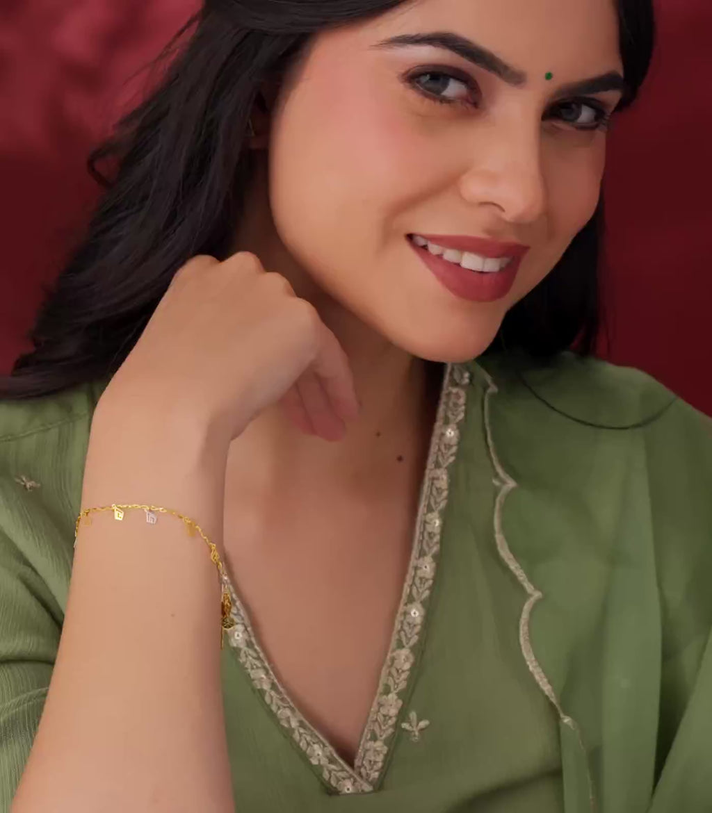 A woman flaunting gold bracelet with geometric charms on a red background